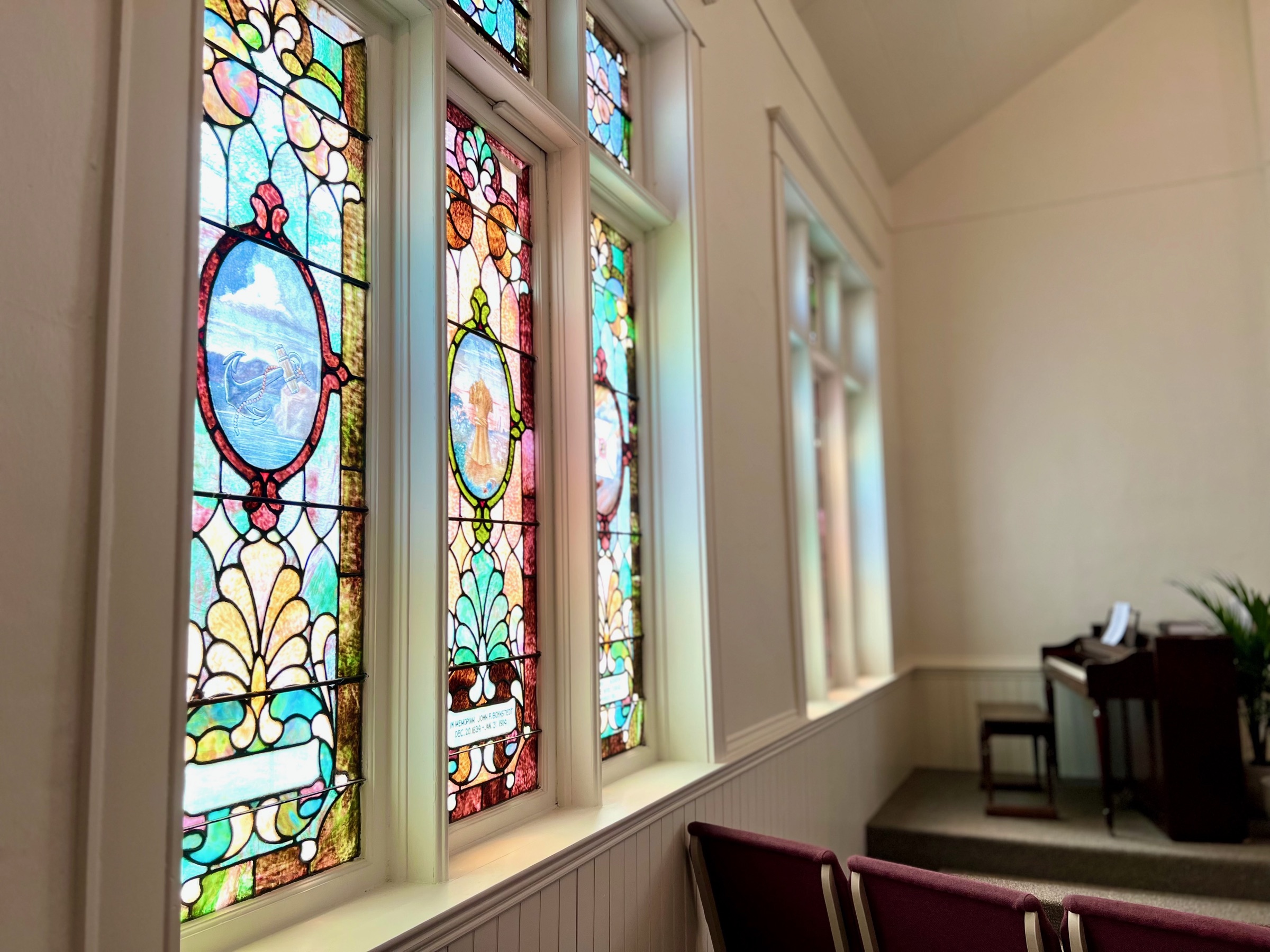 Stained-glass windows and piano in the sanctuary of Grace Reformed Church of Weiser